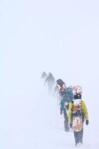 Des randonneurs aventureux traversent un sentier enneigé au milieu d'un blizzard à Niseko, au Japon, mettant en valeur les défis hivernaux.