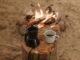 Un cadre serein autour d'un feu de camp avec café et cafetière moka sur une bûche de bois, parfait pour les amoureux du plein air.
